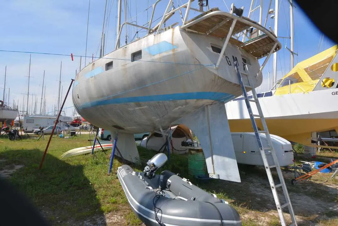 Amateur Reve Des Tropiques — Voilier à double safran posé à terre, avec annexe et échelle au premier plan.