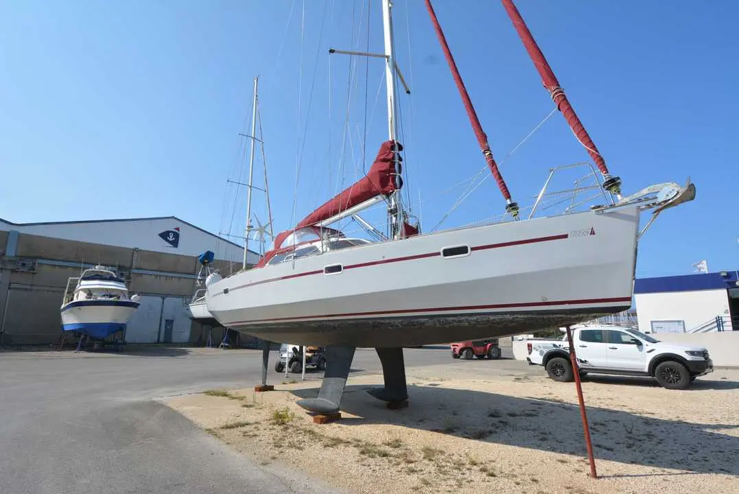 Fora Marine RM 1050 — Voilier blanc à voiles rouges présenté à terre sur bers dans une zone technique.