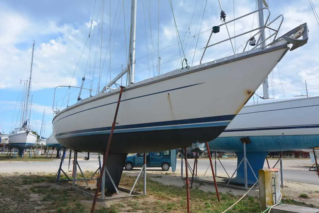 Luffe 46 — Voilier blanc à l'arrêt sur bers dans une zone de maintenance nautique.