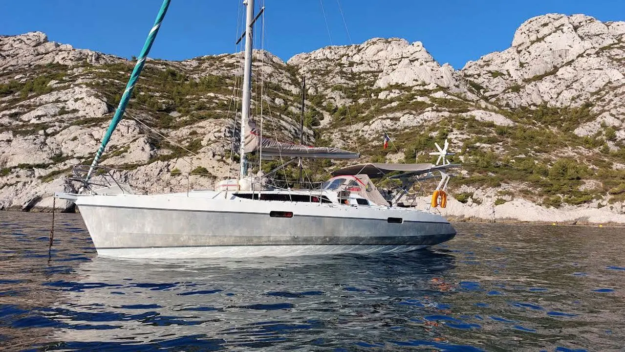 Alubat Ovni 345 Di — Voilier blanc au mouillage devant une côte rocheuse
