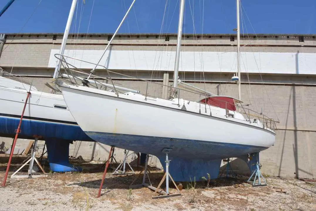 Amel Euros 39 — Voilier blanc sur bers devant un hangar, photographié de trois quarts bâbord.