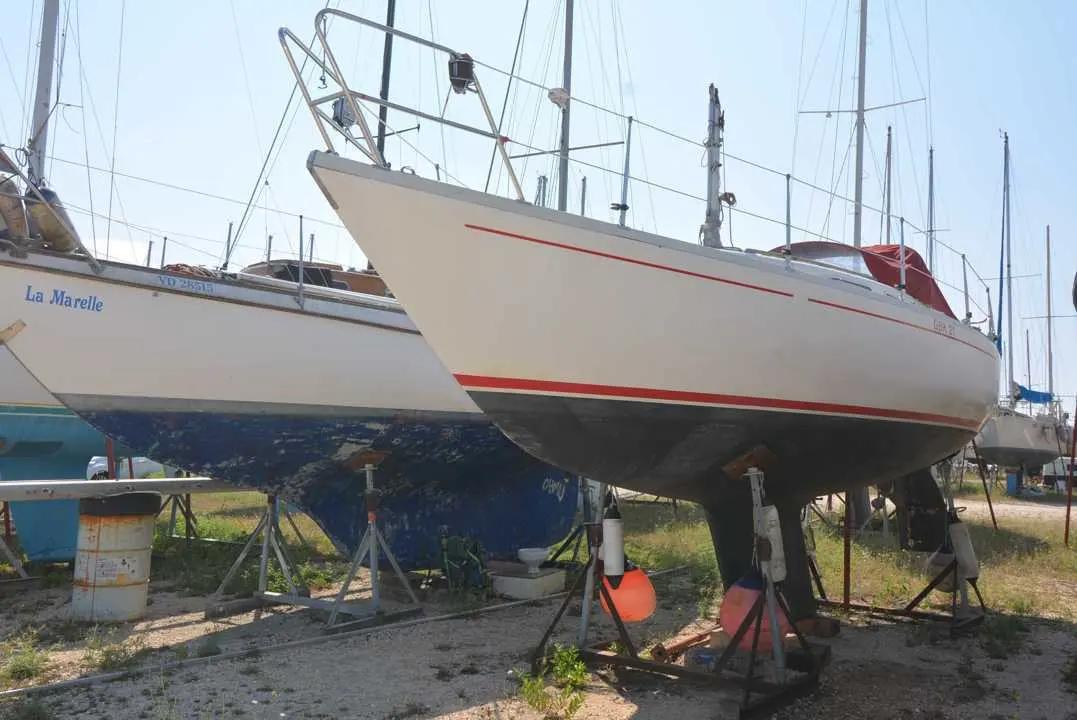 Albin Marine Ballad — Voilier blanc à liserés rouges, présenté à terre sur des bers dans un chantier naval.