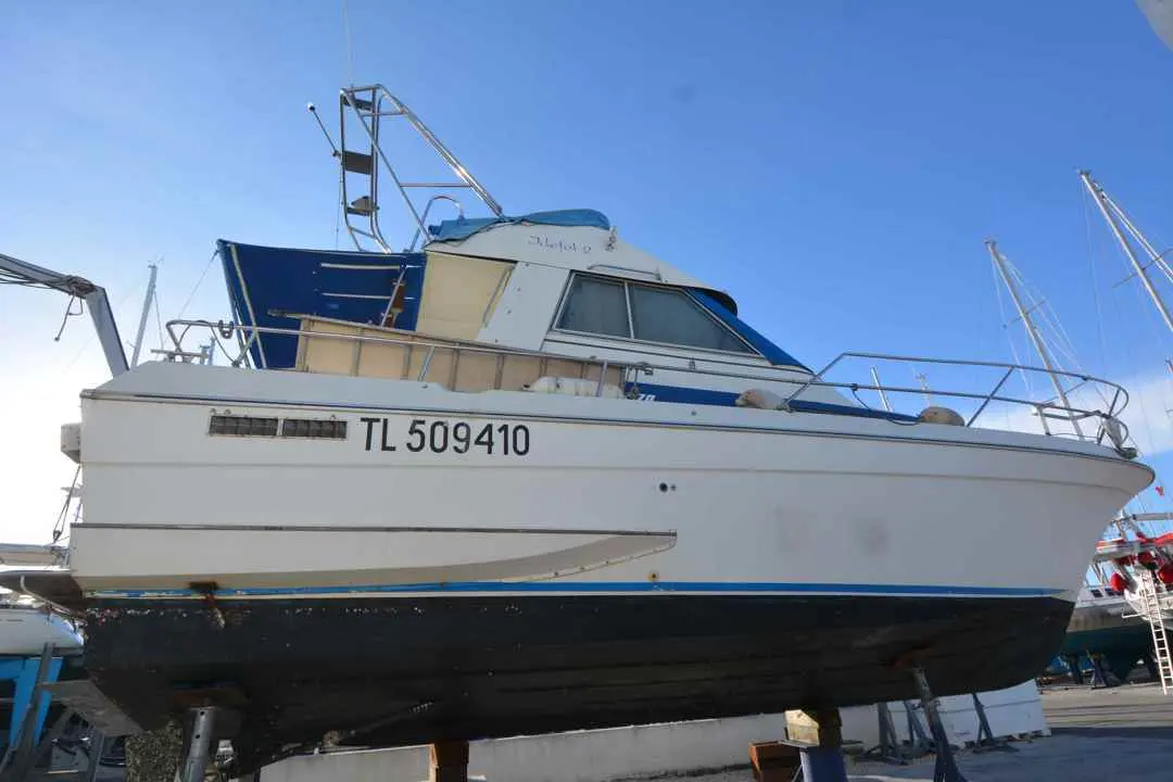 Yachting France Arcoa 970 — Bateau à moteur blanc et bleu photographié à terre, vue latérale.