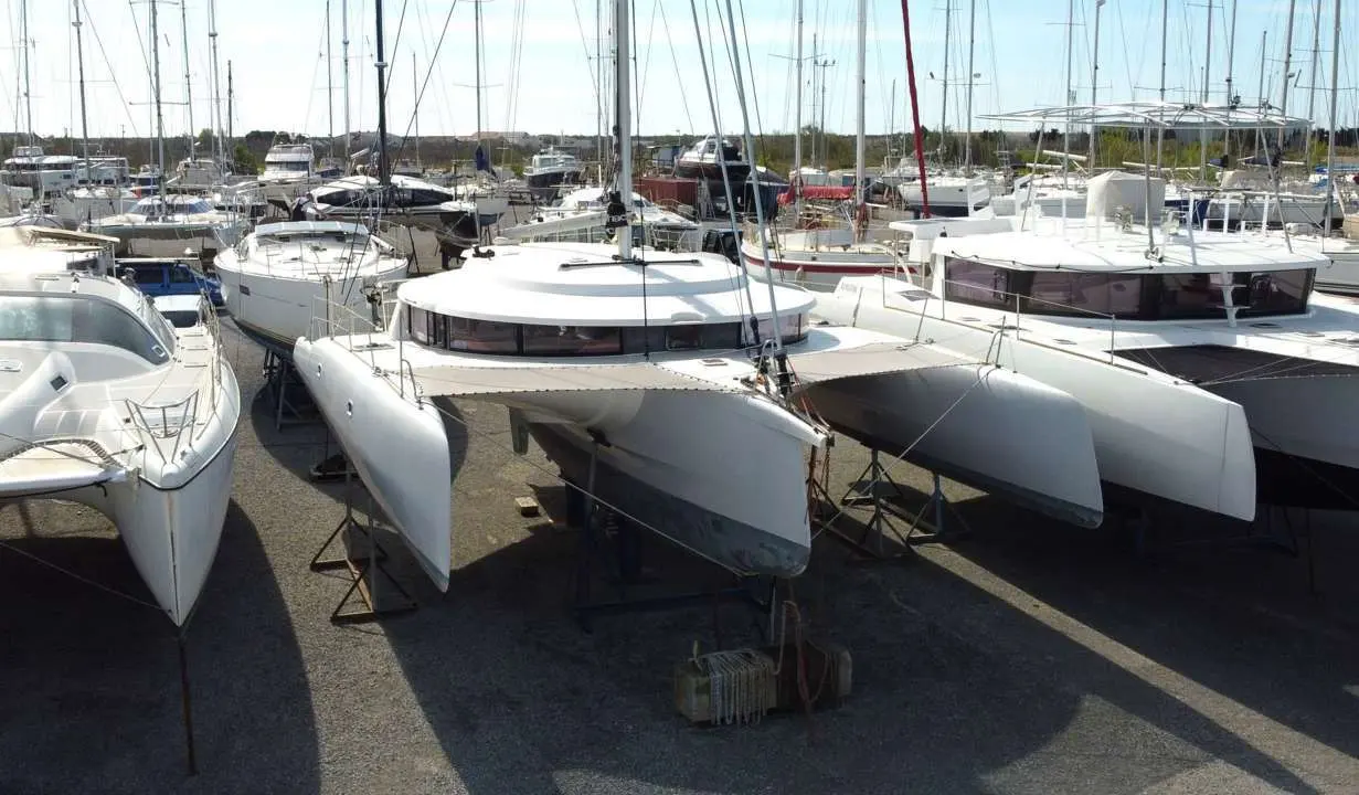 Neel Trimarans Neel 45 — Catamaran blanc à deux coques stationné à terre dans un port à sec.