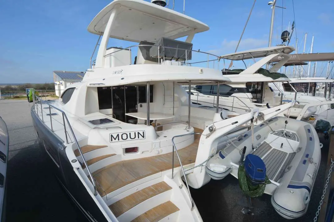 Leopard 47 PC — Vue arrière trois-quarts d’un catamaran blanc amarré, avec annexe sur la plage arrière.