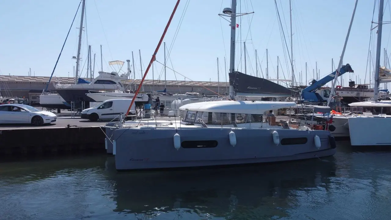 Excess Catamarans Excess 12 — Catamaran blanc amarré dans un port, vu de côté, avec des pare-battages.