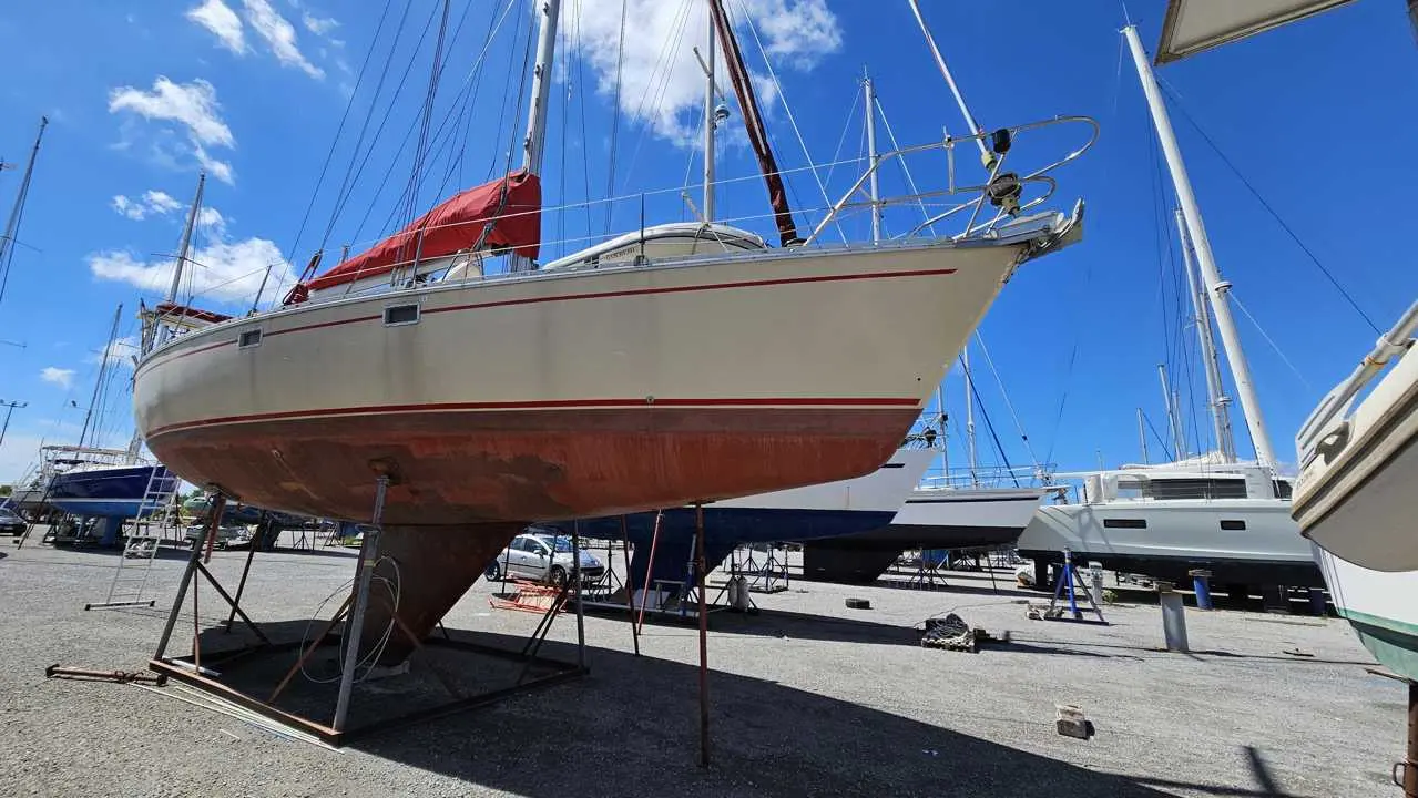 Jeanneau Sun Kiss 45 — Voilier blanc et rouge posé à terre dans une zone de maintenance nautique.