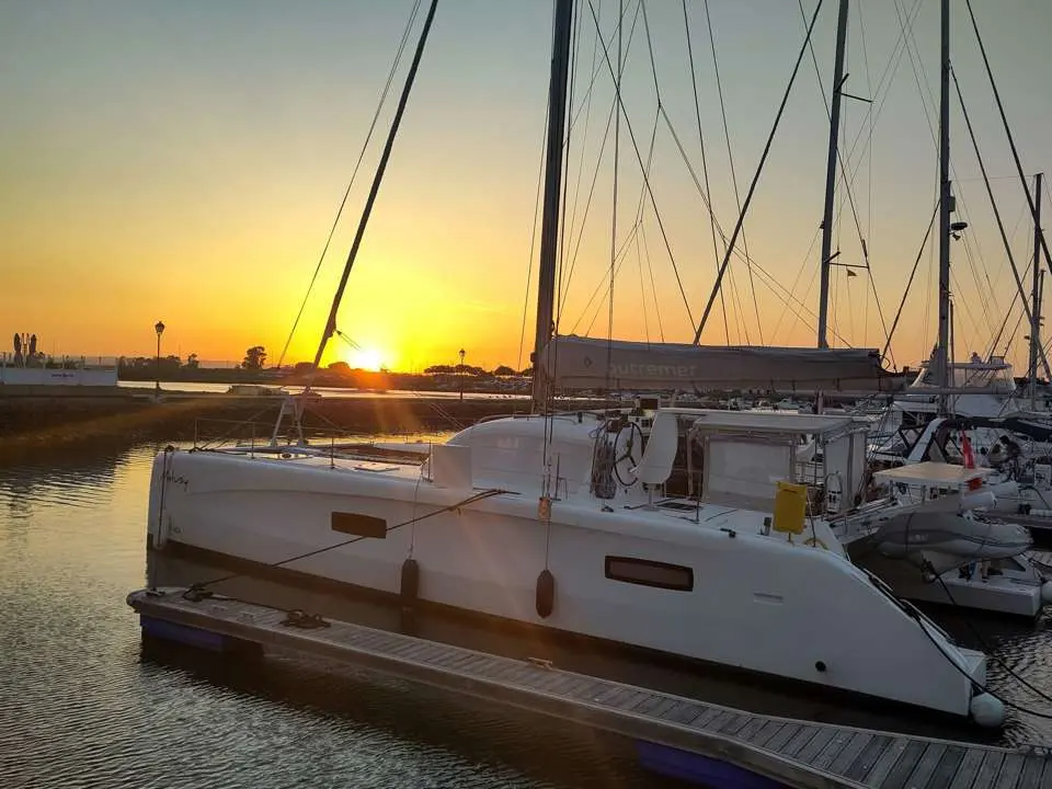 Outremer 45 — Catamaran blanc amarré dans un port au coucher du soleil.