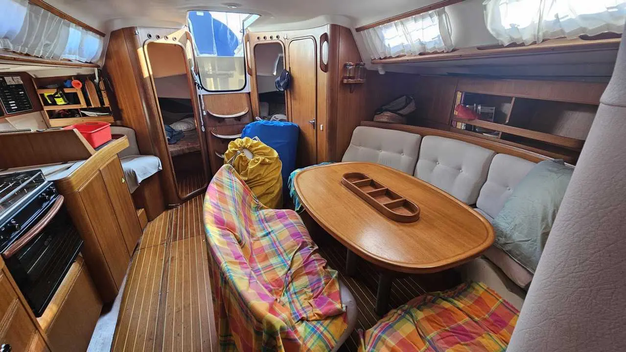 X-Yachts X-412 — Vue du carré intérieur avec table, banquettes, cuisine et cabines accessibles.
