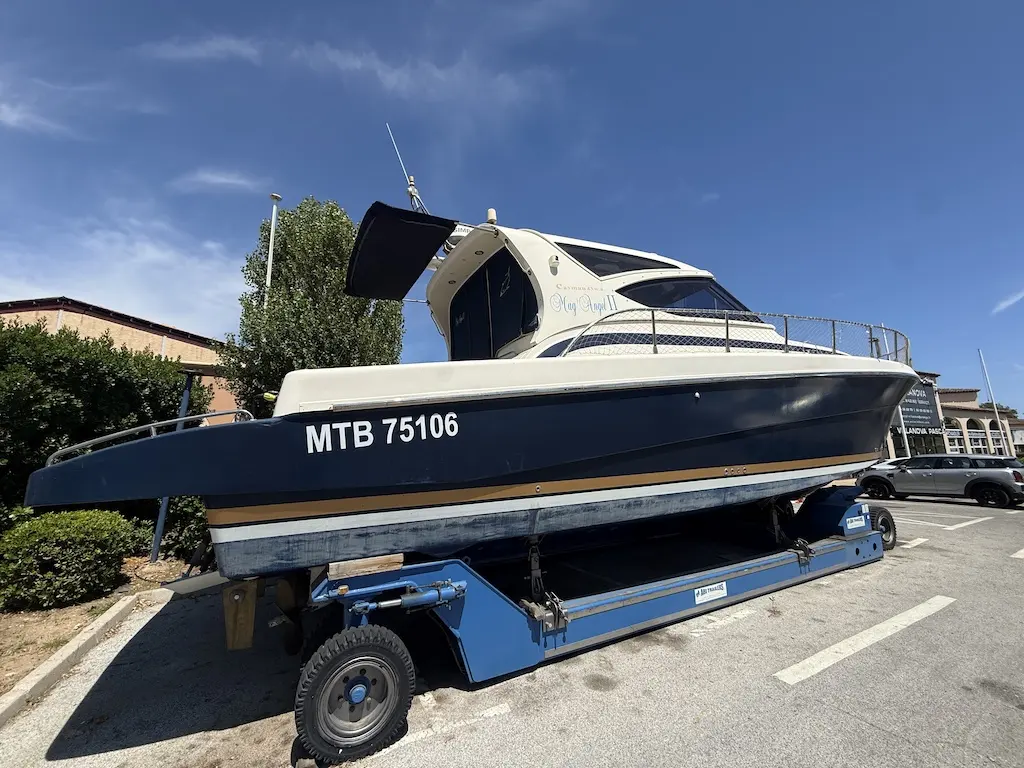 Cayman 43 WA — Bateau à cabine blanche et coque sombre présenté sur une remorque, vu de trois quarts.