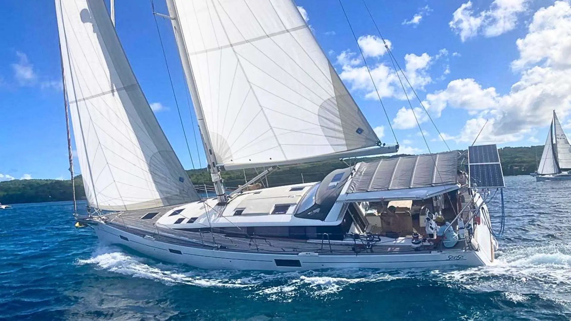 Beneteau Sense 51 — Voilier blanc vu de trois-quarts, toutes voiles hissées, naviguant sur une mer bleue.