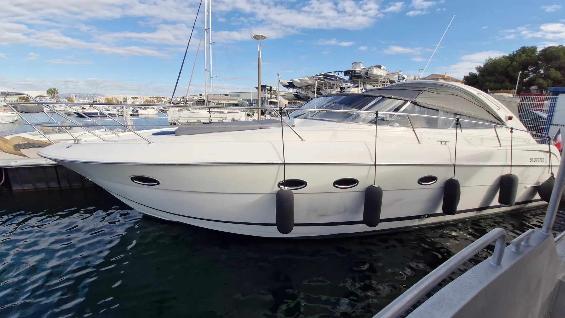 Bavaria 37 — Bateau à moteur blanc amarré dans une marina, vu de profil par tribord.