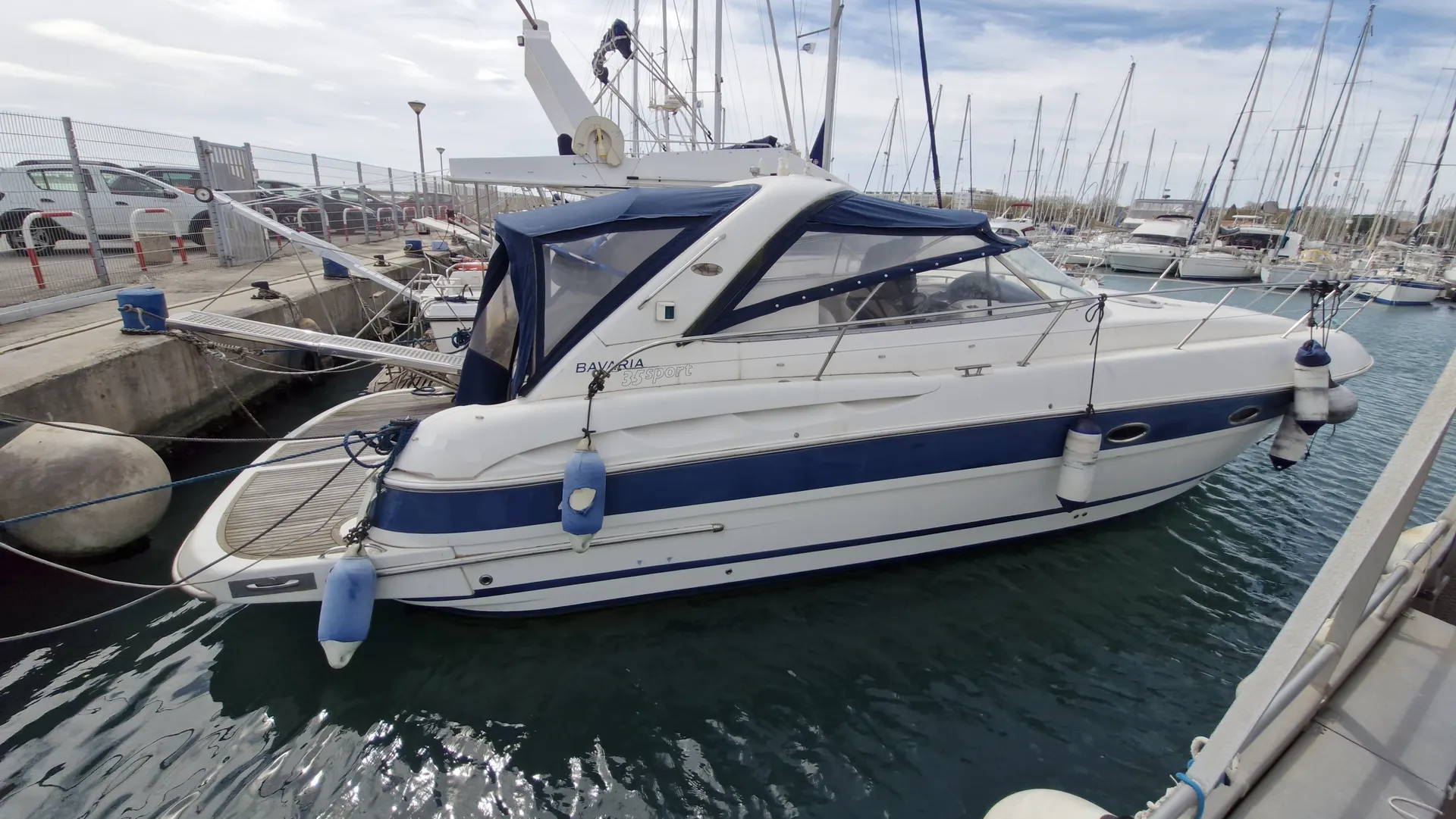 Bavaria 35 — Bateau à moteur blanc et bleu amarré dans un port de plaisance.