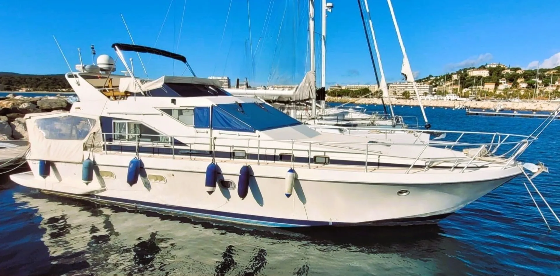 Guy Couach 1401 — Bateau à moteur blanc amarré dans un port, vu de trois quarts.