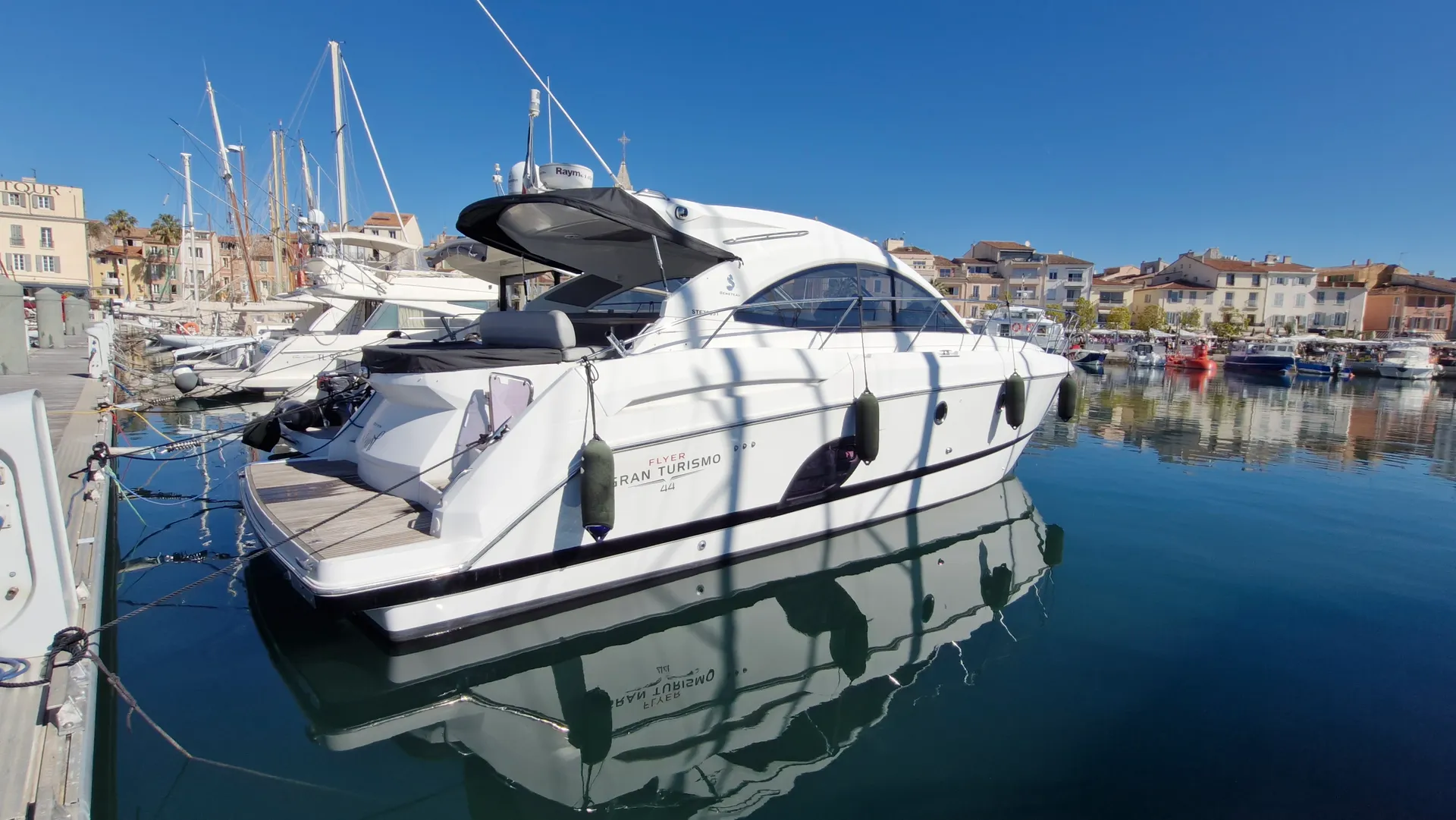 Beneteau GT 44 — Bateau à moteur blanc vu de trois quarts arrière dans un port de plaisance.