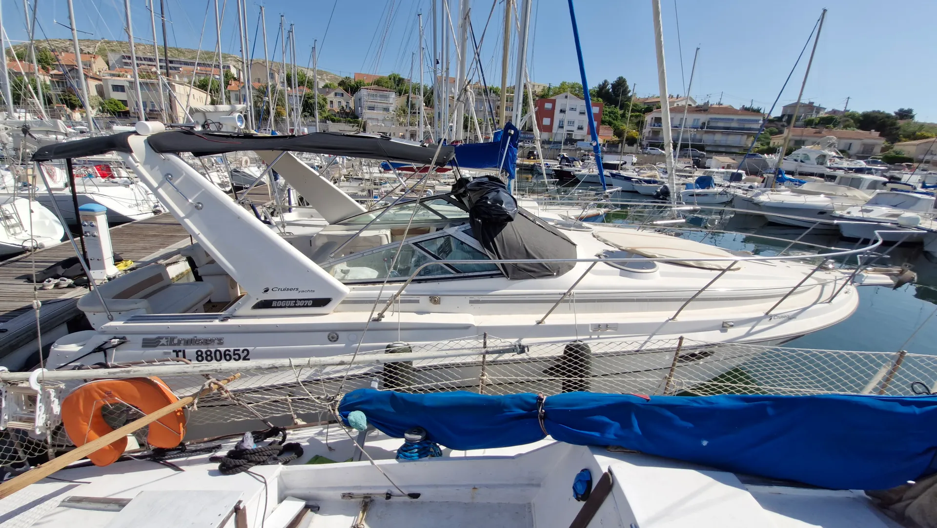 Cruisers Yachts 3070 Rogue — Bateau à moteur blanc amarré dans un port, vu de profil entre d'autres embarcations.