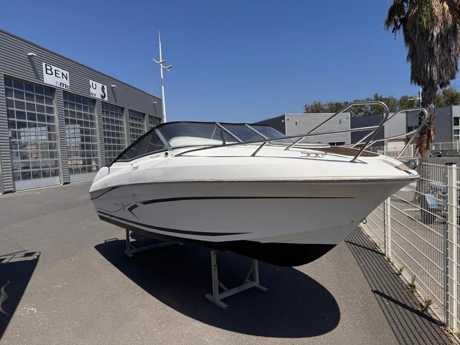 Beneteau Flyer 650 Cabrio — Bateau à moteur blanc présenté sur remorque devant un bâtiment professionnel.