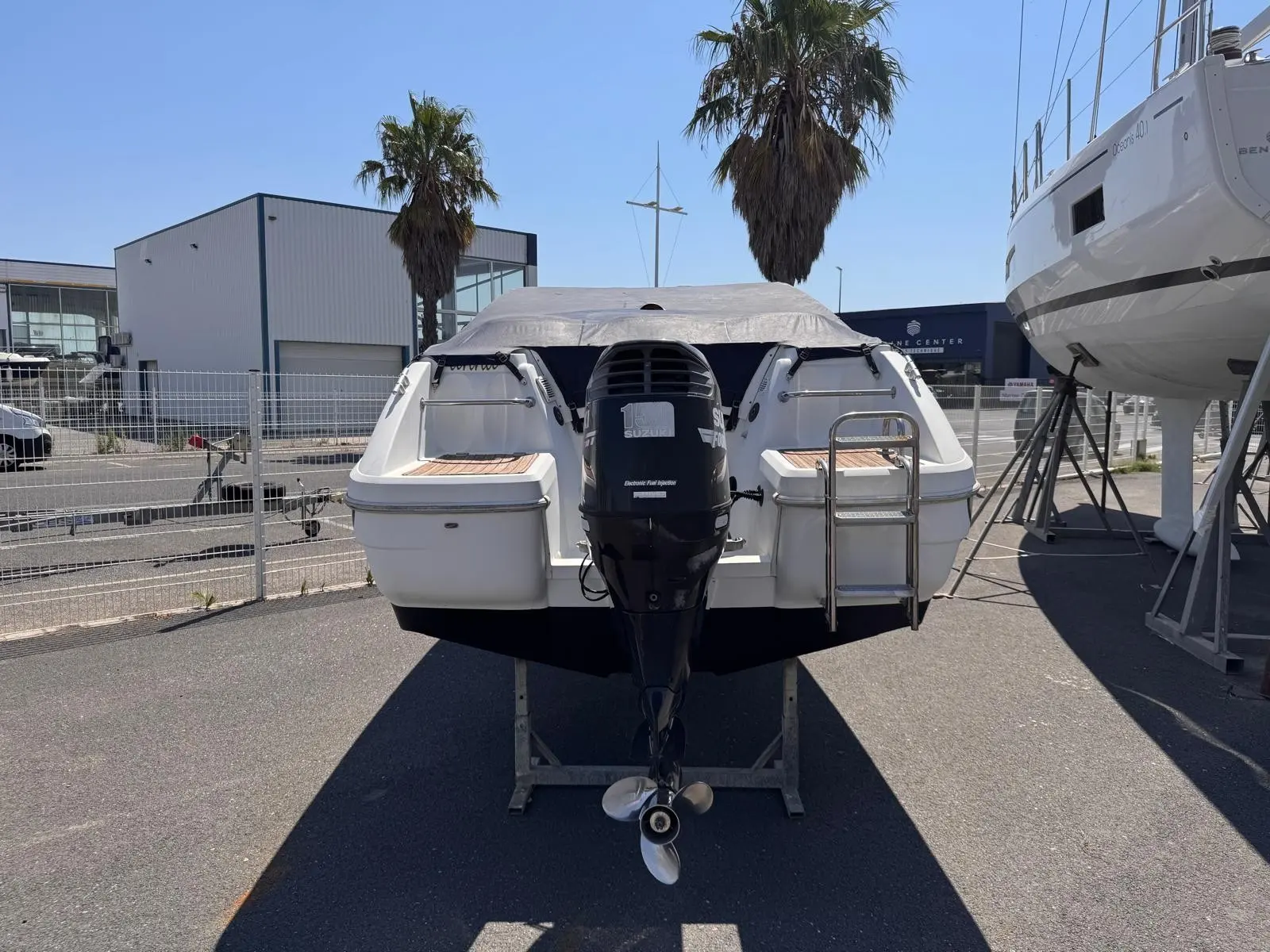 Beneteau Flyer 650 Cabrio — Vue arrière d’un bateau exposé à terre, avec moteur hors-bord et hélice visibles.