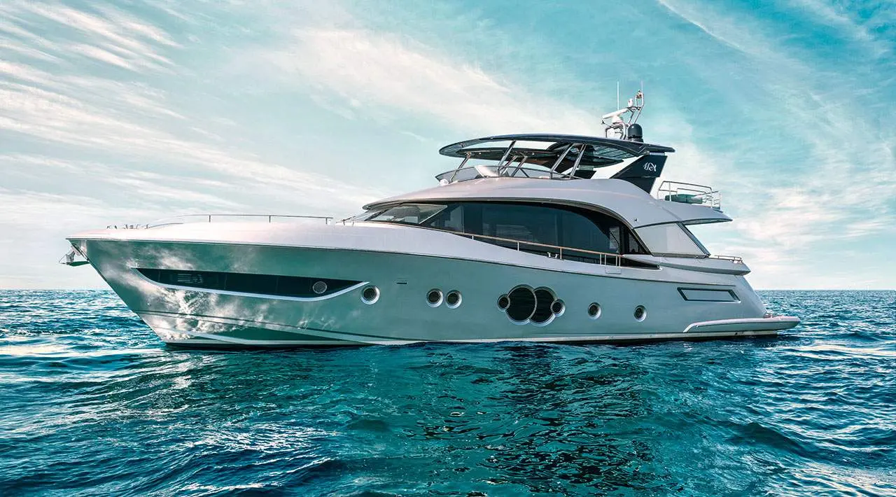 Monte Carlo MCY 76 — Bateau à moteur vu de profil sur une mer turquoise, sous un ciel nuageux.