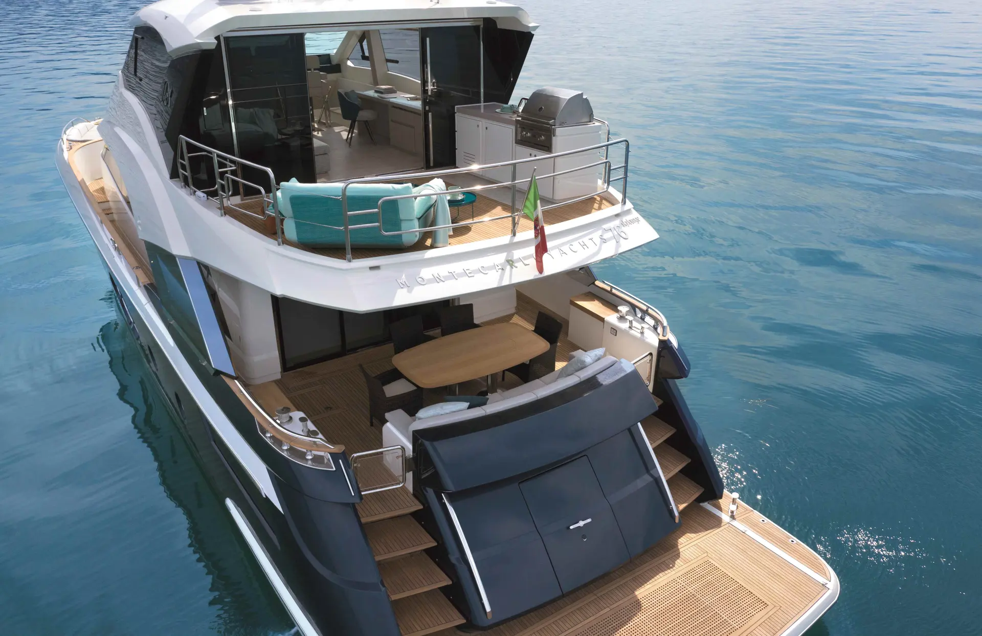 Monte Carlo MCY 76 — Vue arrière trois quarts d’un yacht blanc avec deux niveaux de terrasse et plateforme.