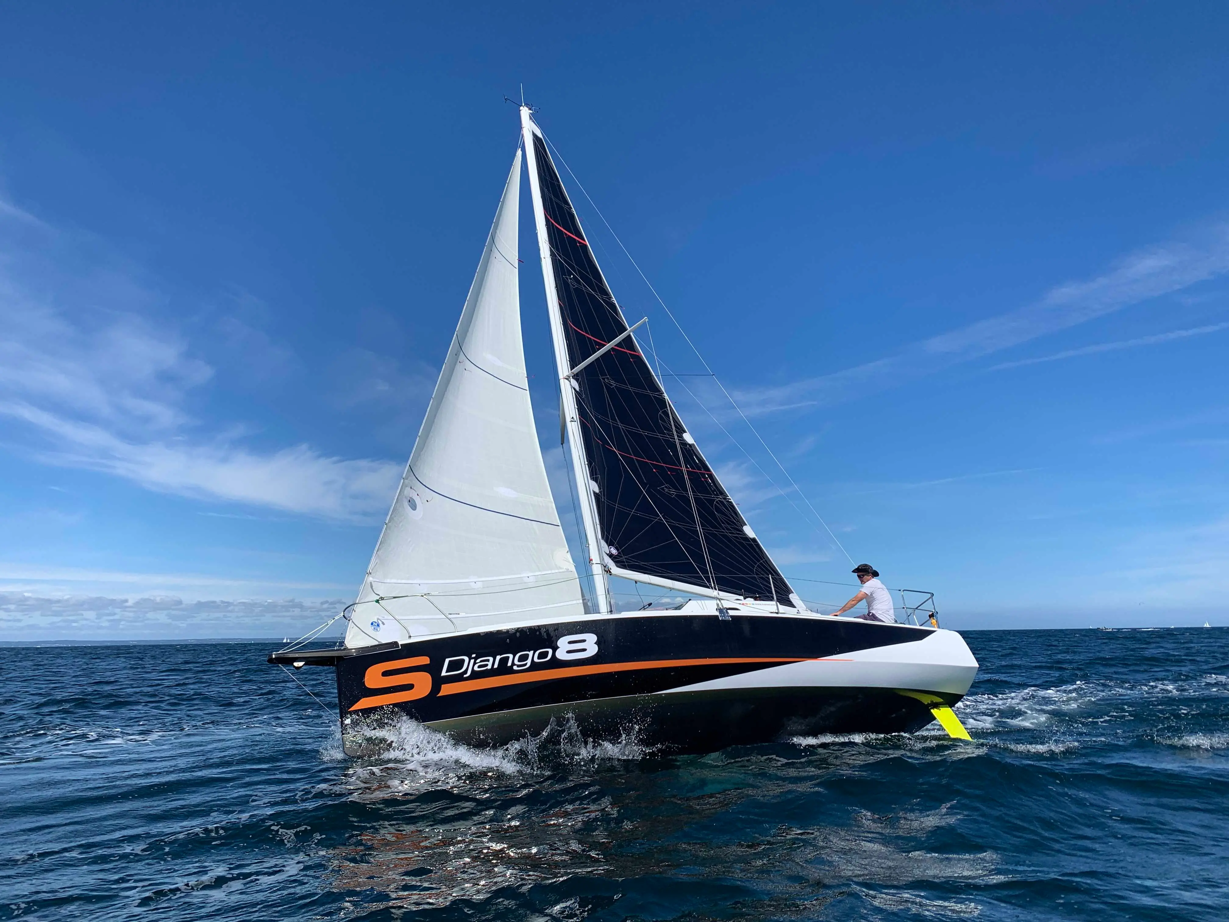 Maree Haute Django 8S — Voilier noir et blanc naviguant sous voiles au large.
