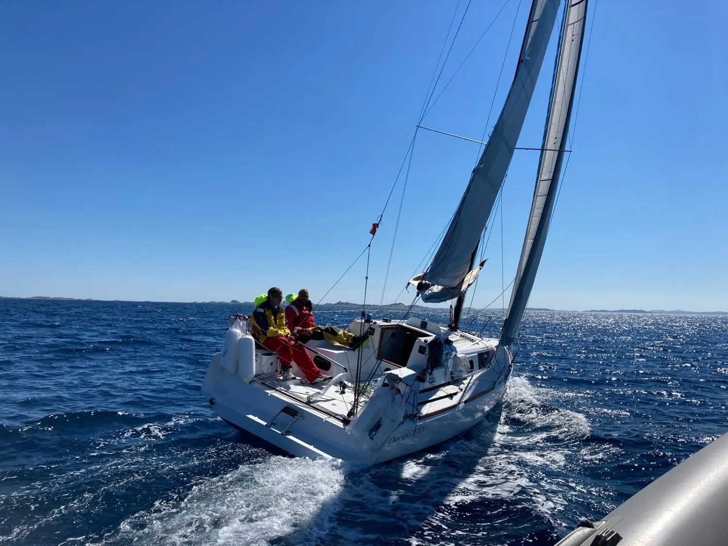 Maree Haute Django 770 — Voilier naviguant au large avec plusieurs personnes à bord par mer ensoleillée.