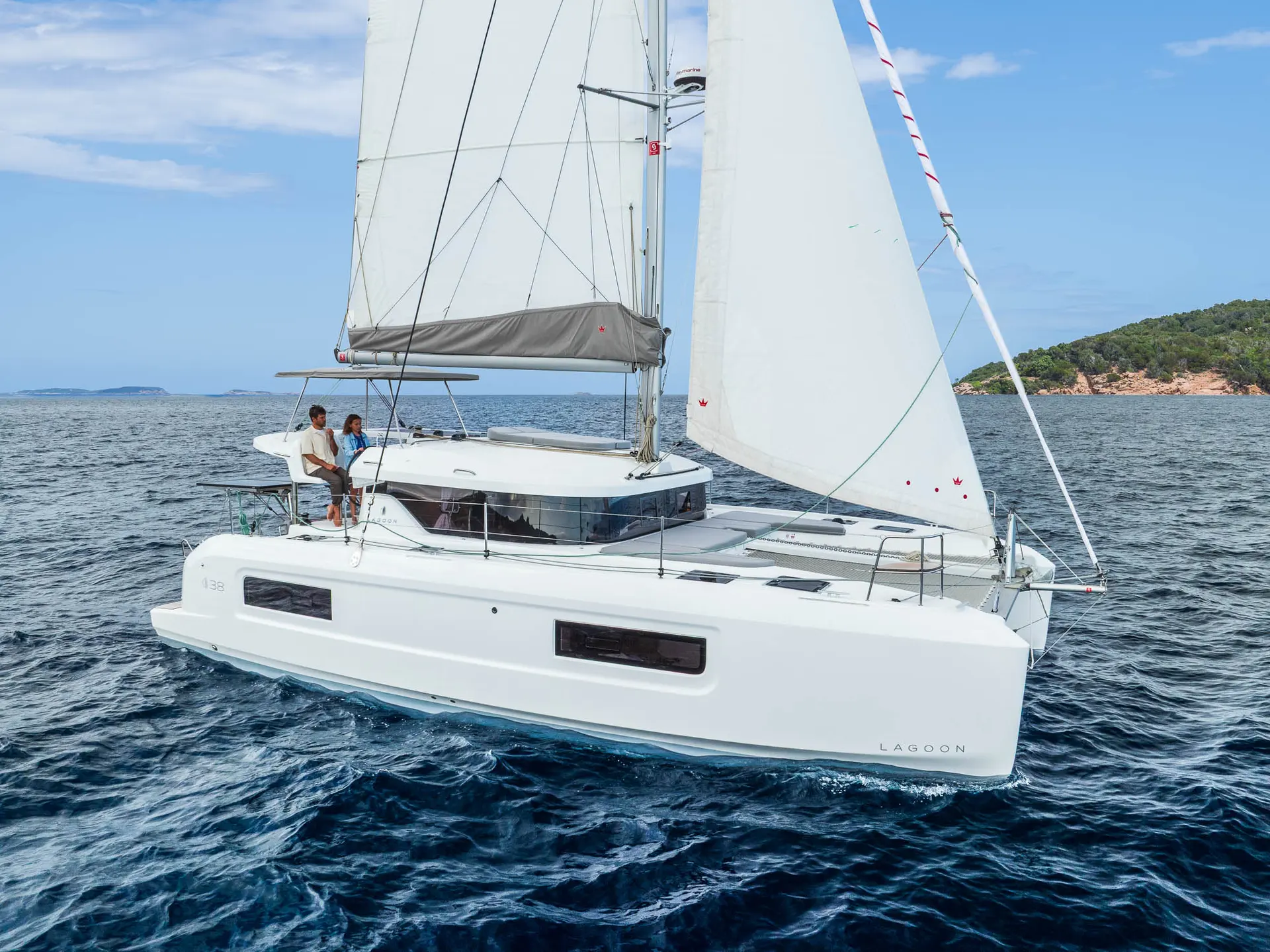 Lagoon 38 — Catamaran à voile blanc naviguant au large d’une côte boisée