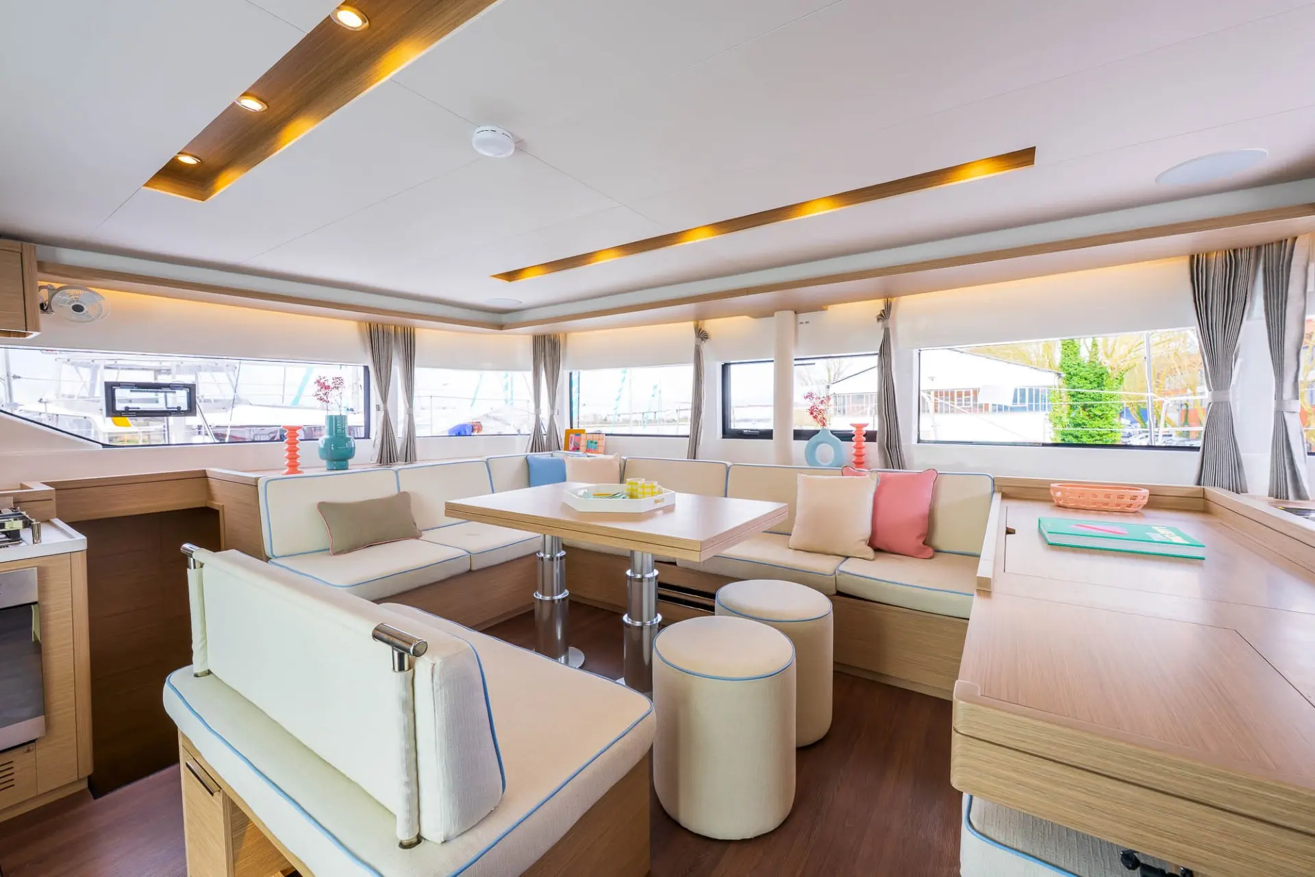 Lagoon 51 — Salon intérieur lumineux avec banquettes, table et larges fenêtres.