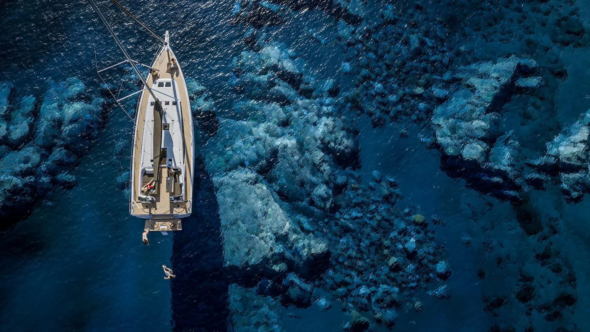 Jeanneau Sun Odyssey 455 — Voilier vu du dessus dans une mer limpide aux fonds rocheux.