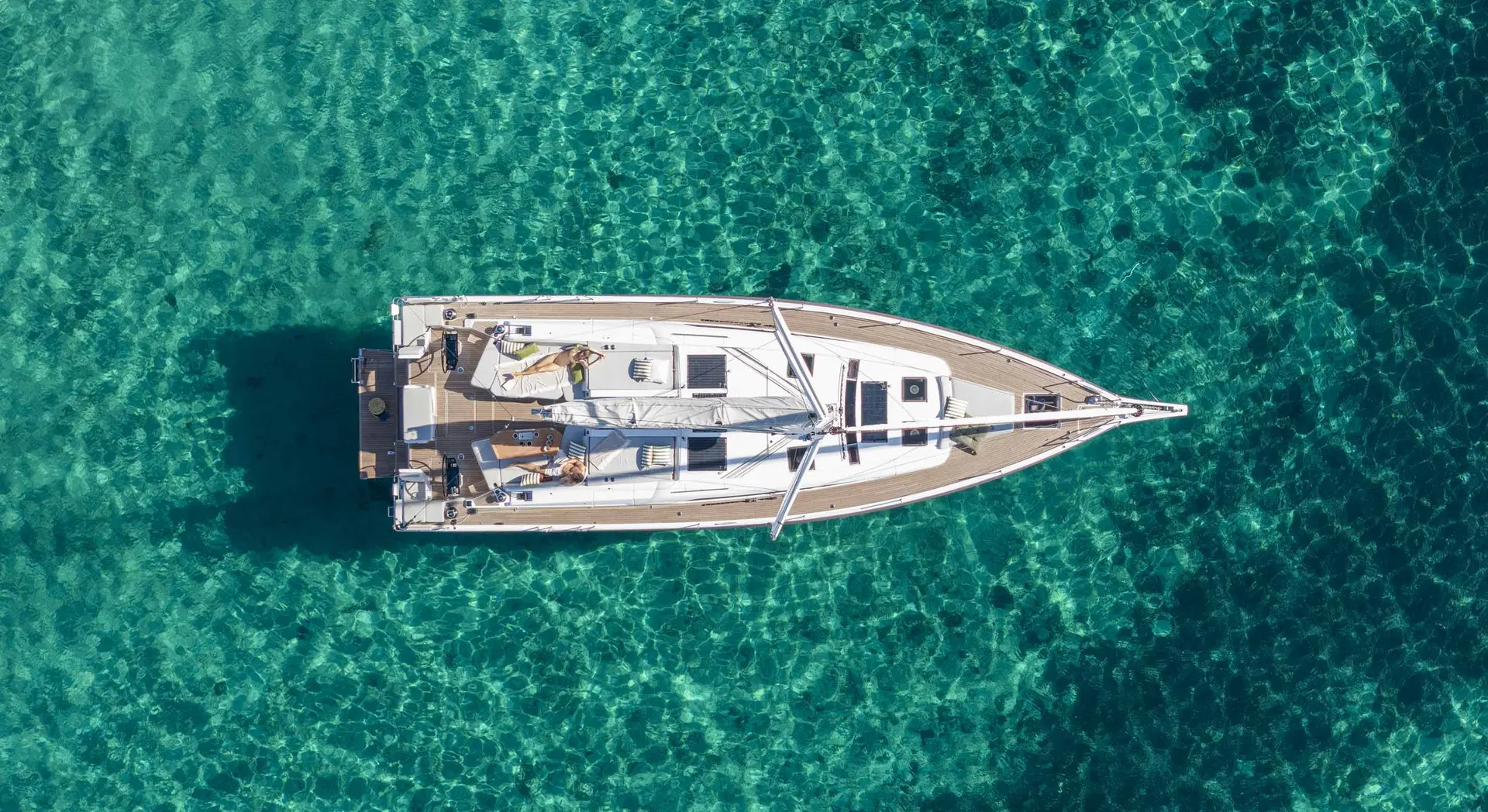 Beneteau Oceanis 52 — Vue aérienne d’un voilier blanc entouré d’une eau turquoise.