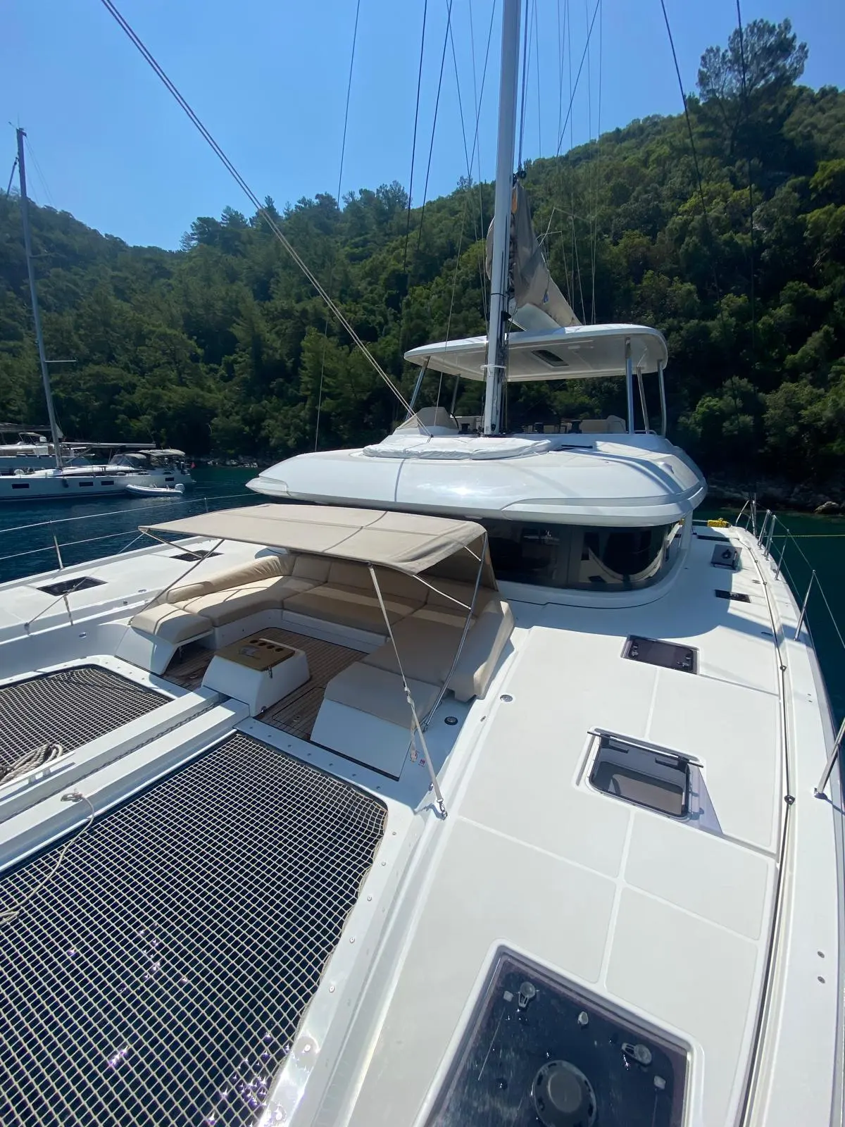 Lagoon 55 — Vue avant d’un catamaran blanc amarré dans une baie boisée.