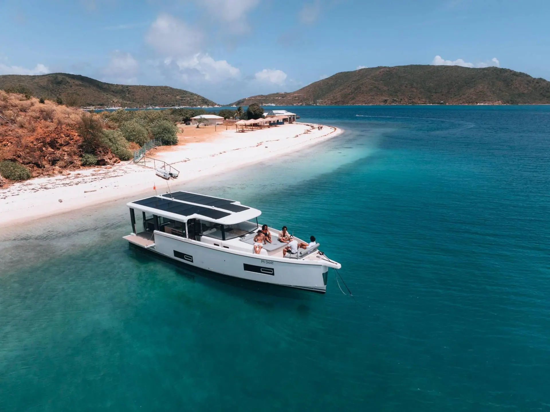 Jeanneau Sea Loft 480 — Bateau à moteur blanc au mouillage près d’une plage tropicale.