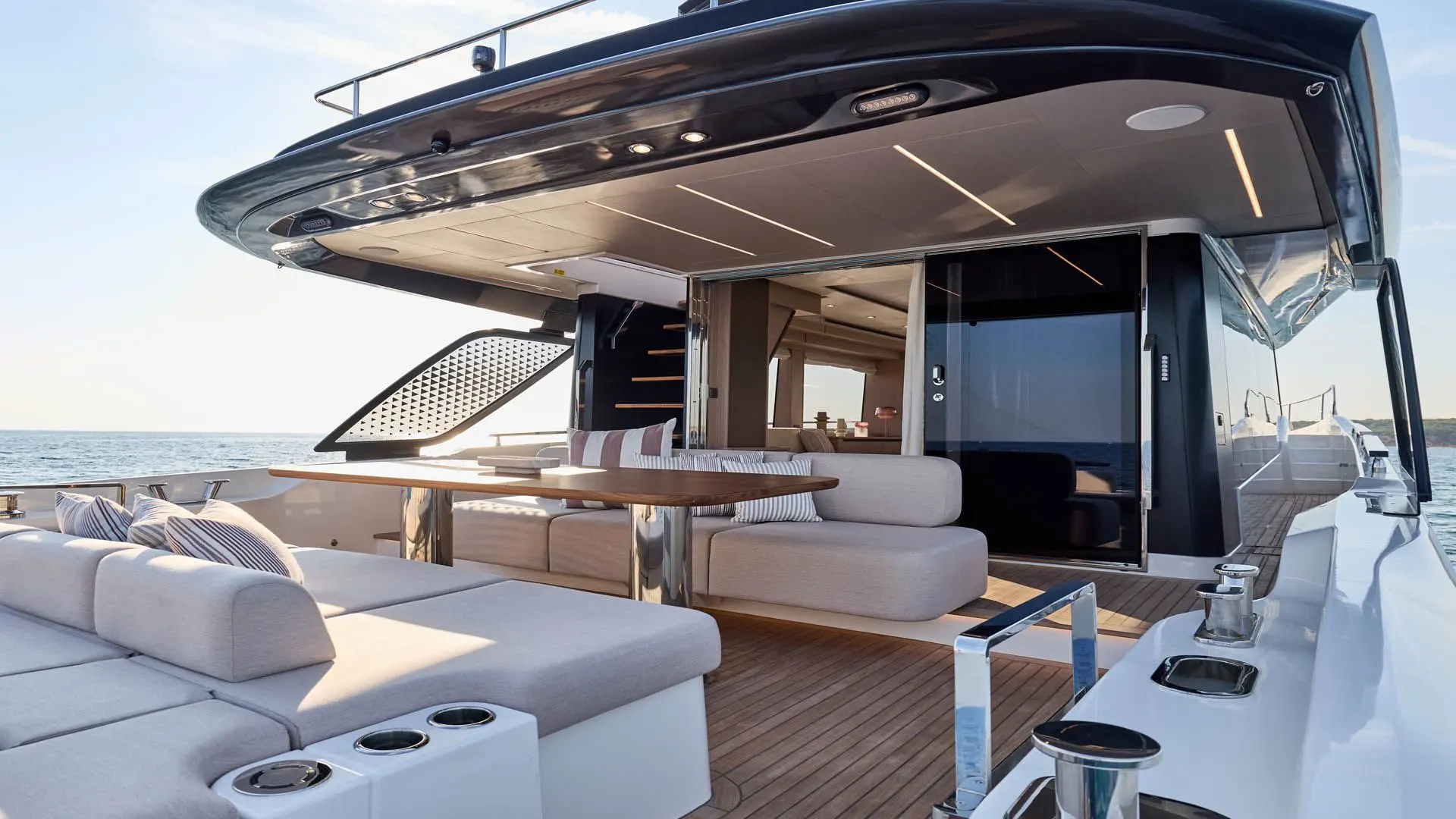 Prestige Yachts F6.7 — Vue de l’espace extérieur arrière avec salon, table et poste de pilotage.