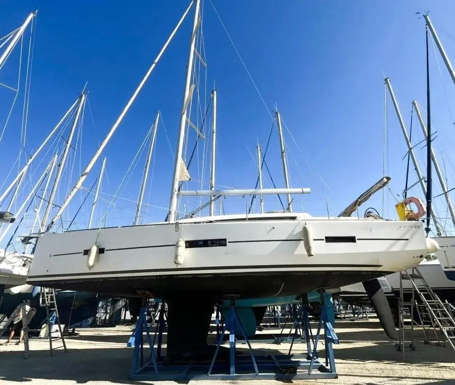 Dufour 410 — Voilier blanc vu de profil, posé sur bers dans un chantier nautique.