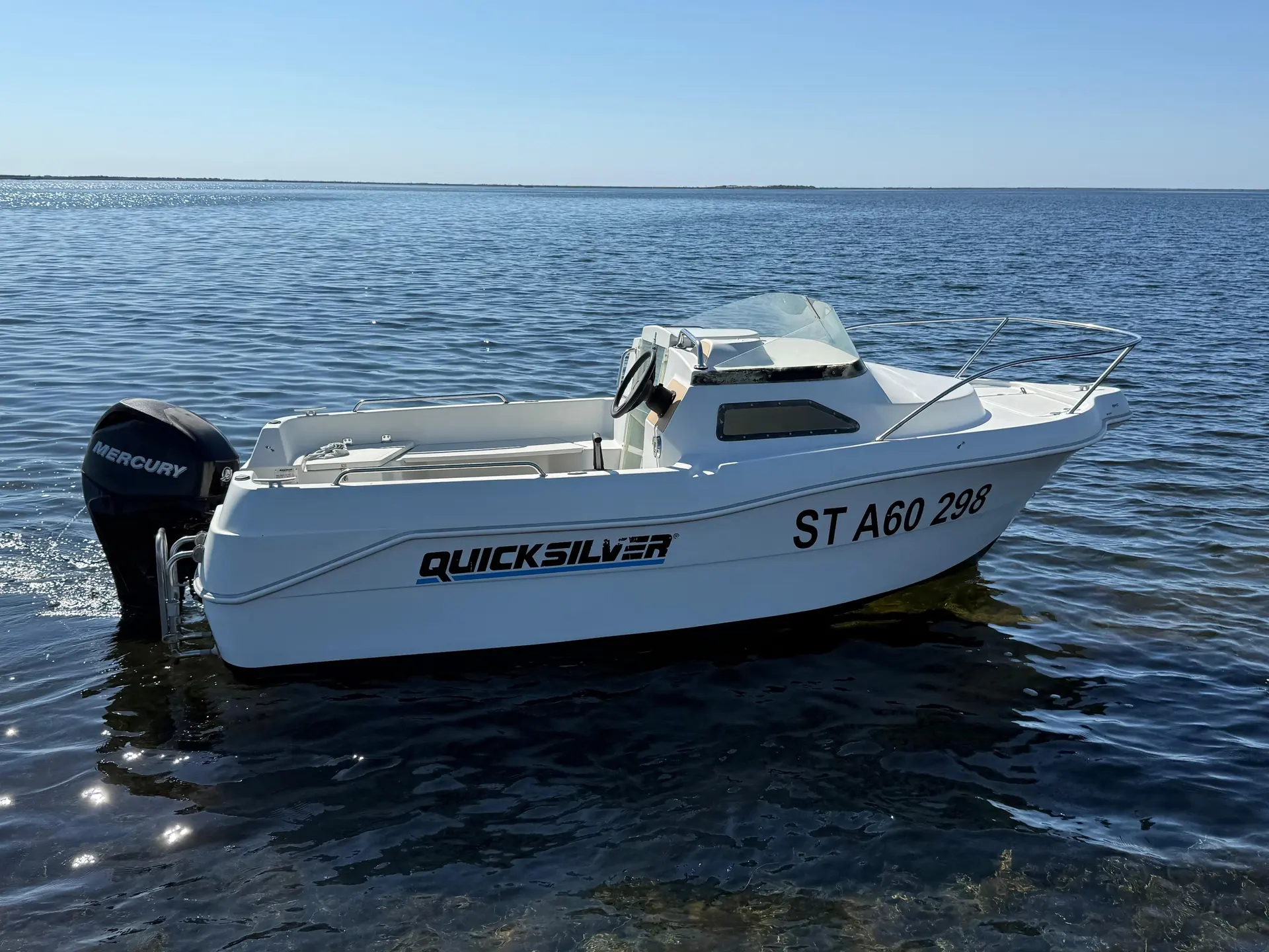 Quicksilver 435 Cabine — Bateau à moteur blanc vu de trois quarts sur une mer calme.