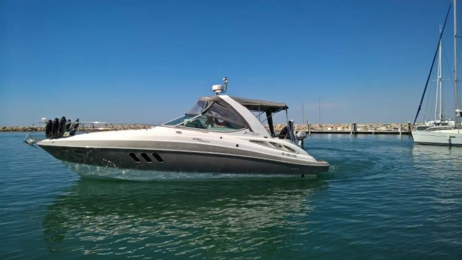 Cruisers Yachts 330 Express — Bateau à moteur photographié de profil dans un port, sur une eau calme.
