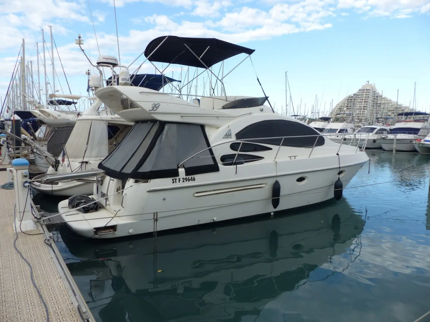 Azimut 39 — Bateau à moteur blanc amarré dans une marina, vu de trois quarts arrière.