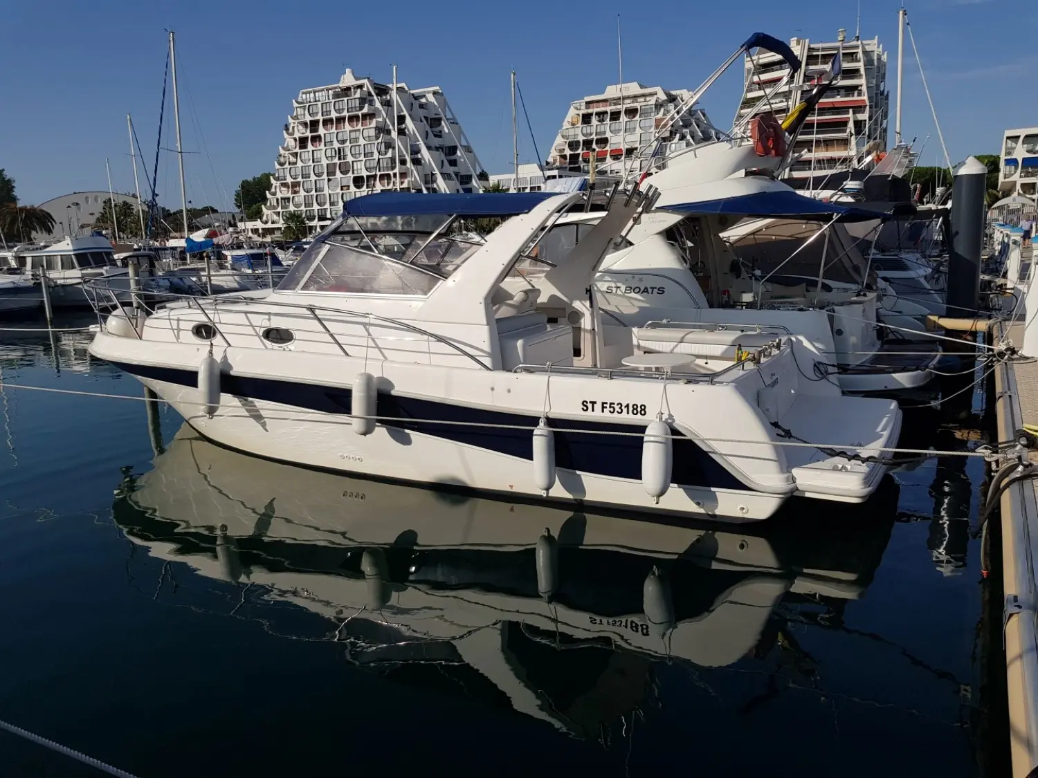 Faeton 980 Open — Bateau à moteur blanc vu de trois quarts dans un port de plaisance.