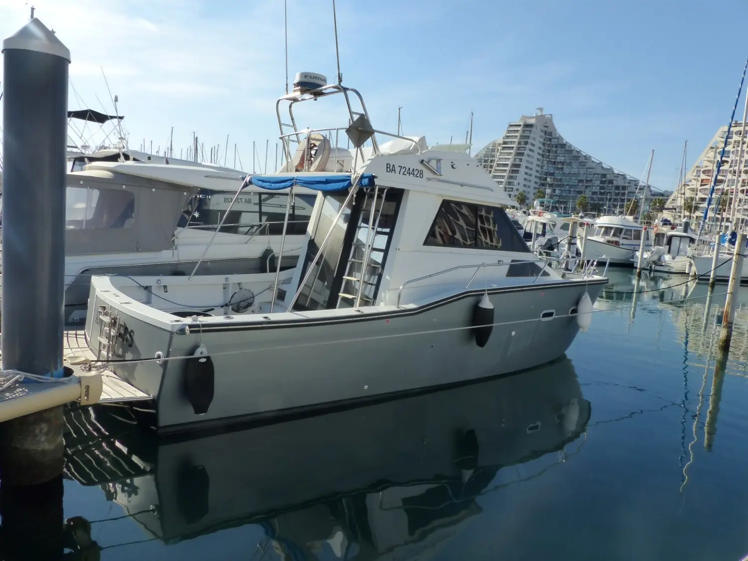 Jeanneau Merry Fisher 930 — Bateau à moteur amarré dans une marina, vu de trois quarts arrière.