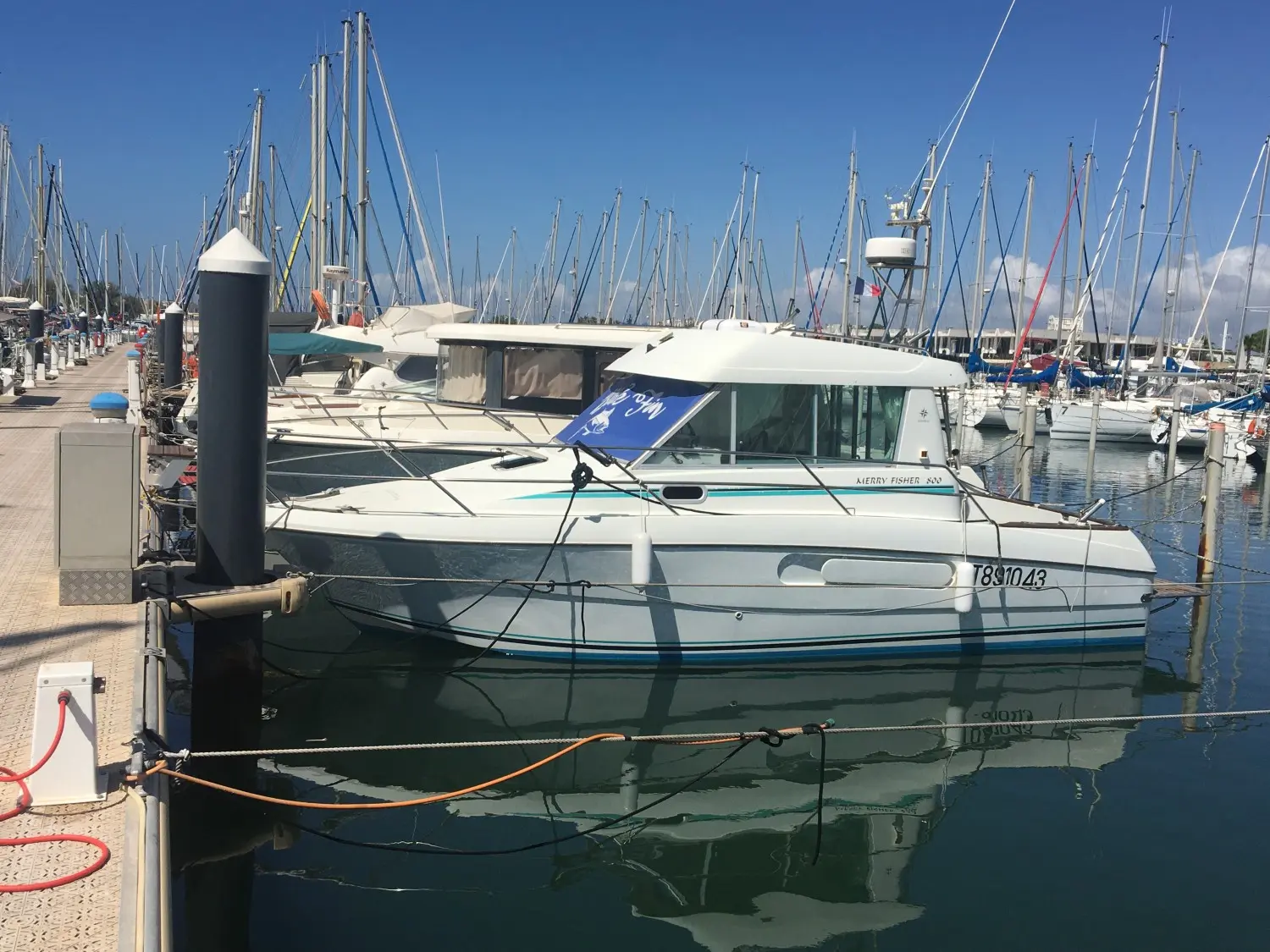 Jeanneau Merry Fisher 800 — Bateau à moteur amarré dans une marina, photographié de profil.