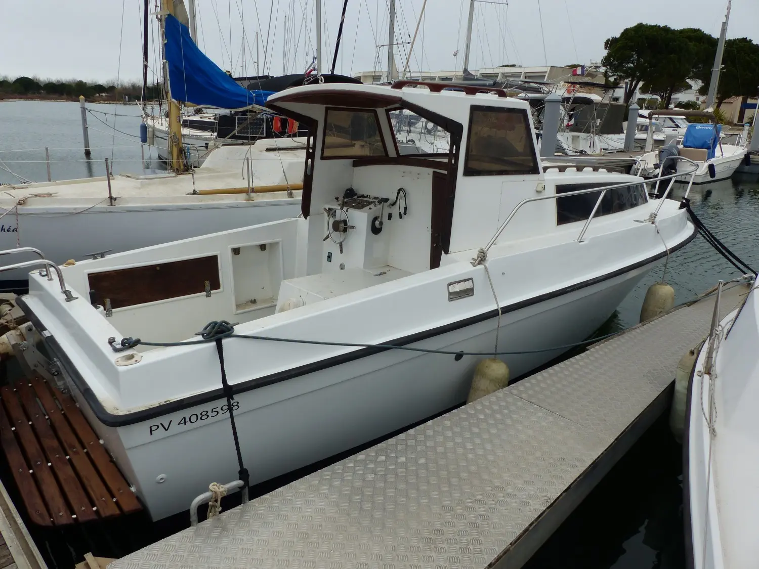 Ocqueteau 645 — Bateau à cabine blanche amarré dans un port, vu de trois quarts arrière.
