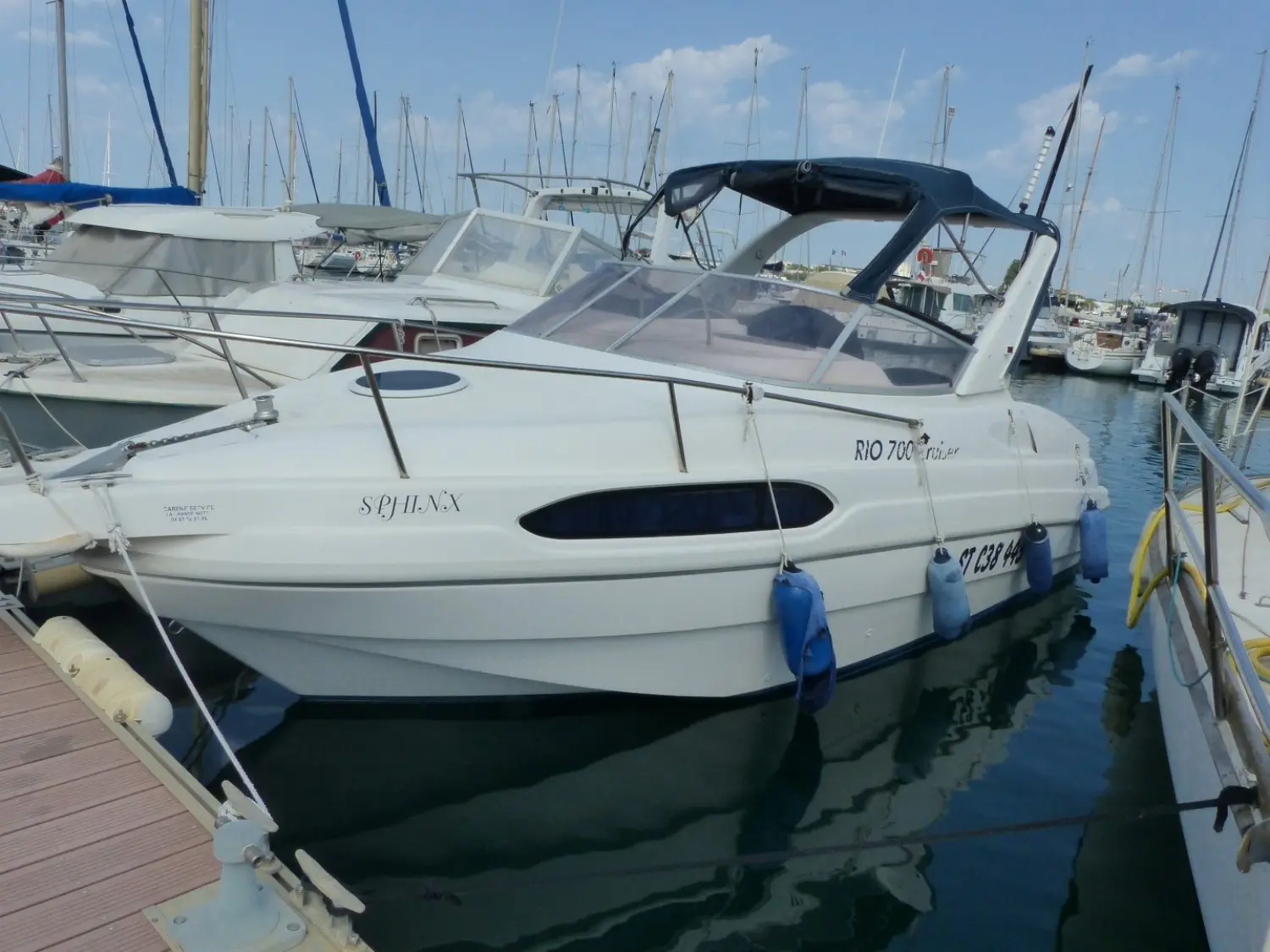 Rio 700 — Bateau à moteur blanc amarré dans un port, vu de trois quarts bâbord.