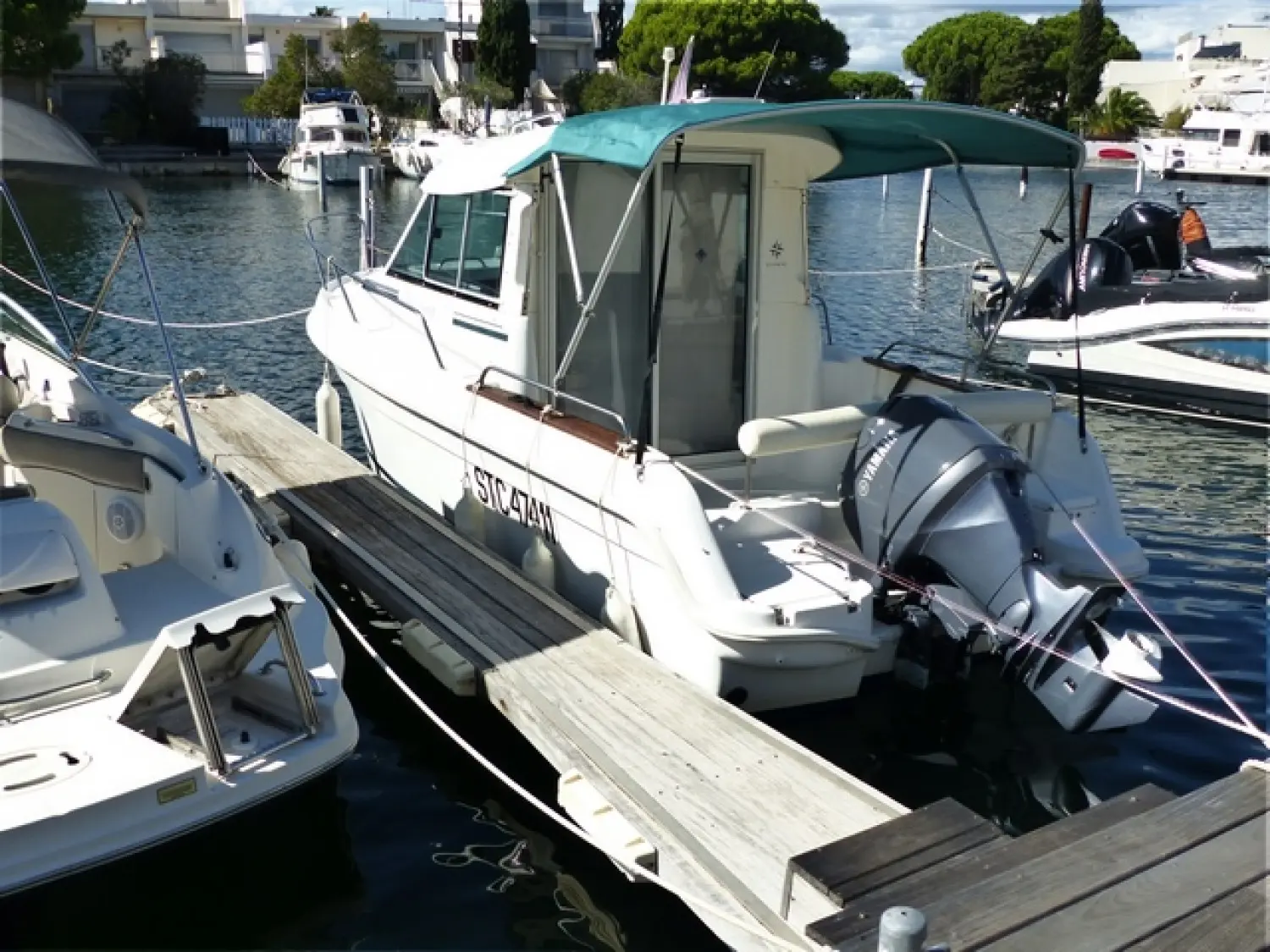 Jeanneau Merry Fisher 625 — Bateau à moteur amarré dans une marina, vu de trois quarts arrière.