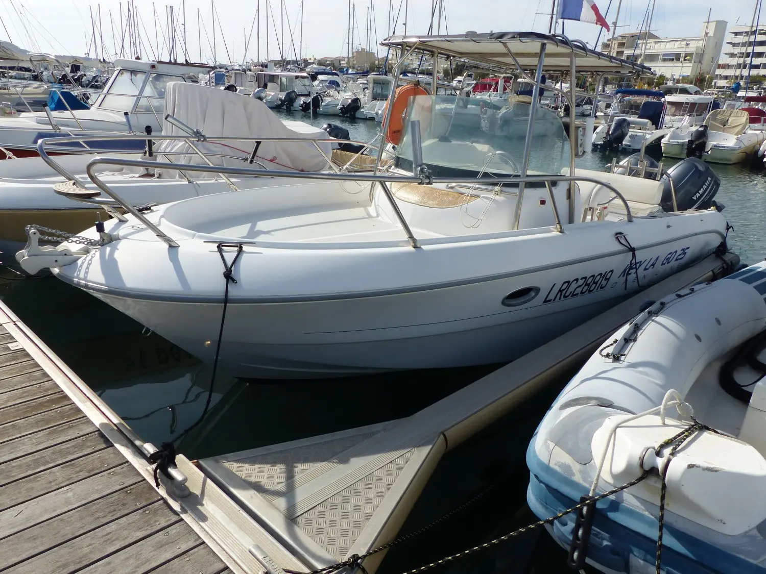 Sessa Marine Key Largo 25 — Bateau à moteur blanc vu de trois quarts dans un port de plaisance.