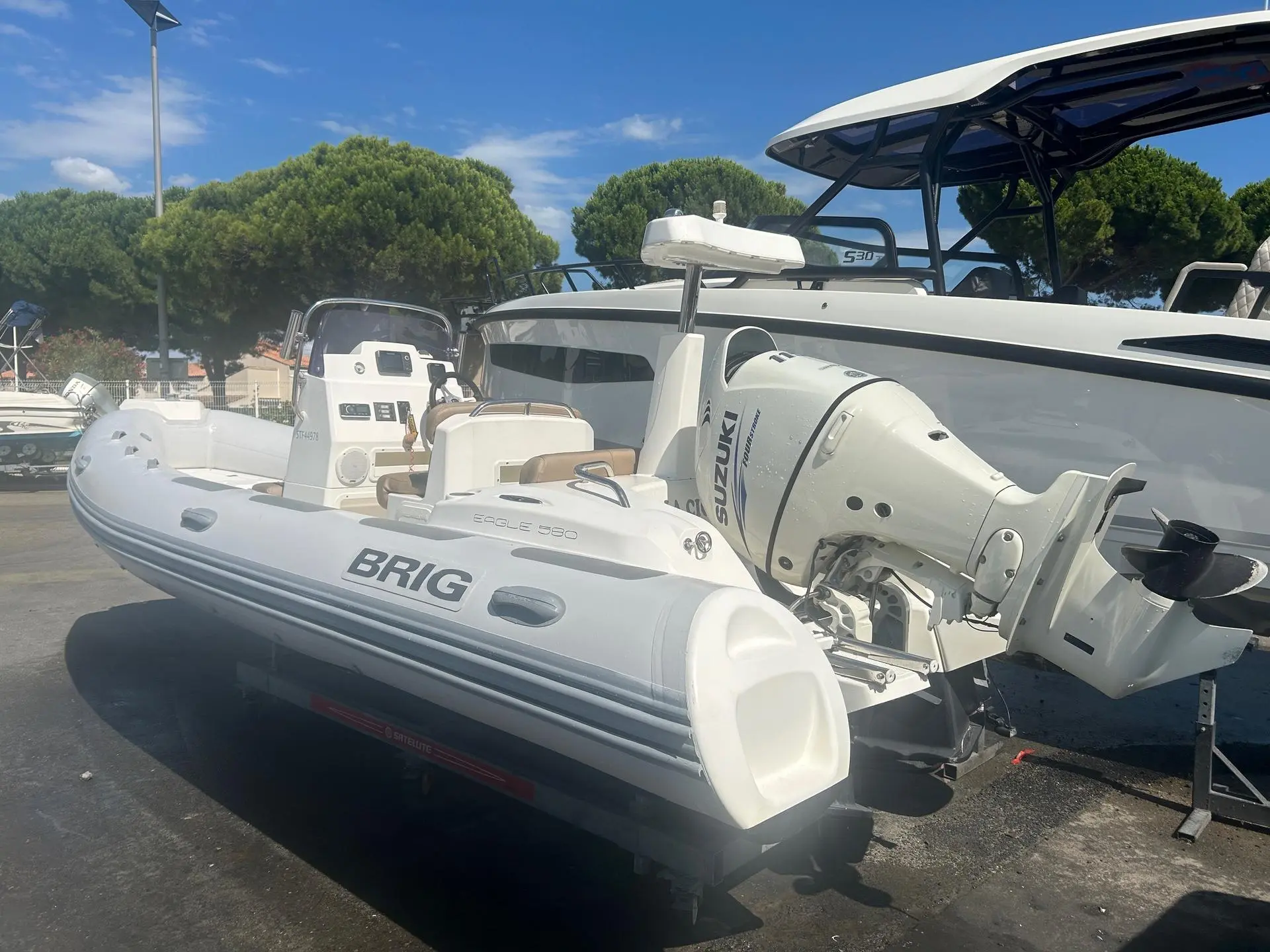 Brig Eagle 580 — Bateau pneumatique blanc équipé d’un moteur hors-bord Suzuki, photographié à terre.