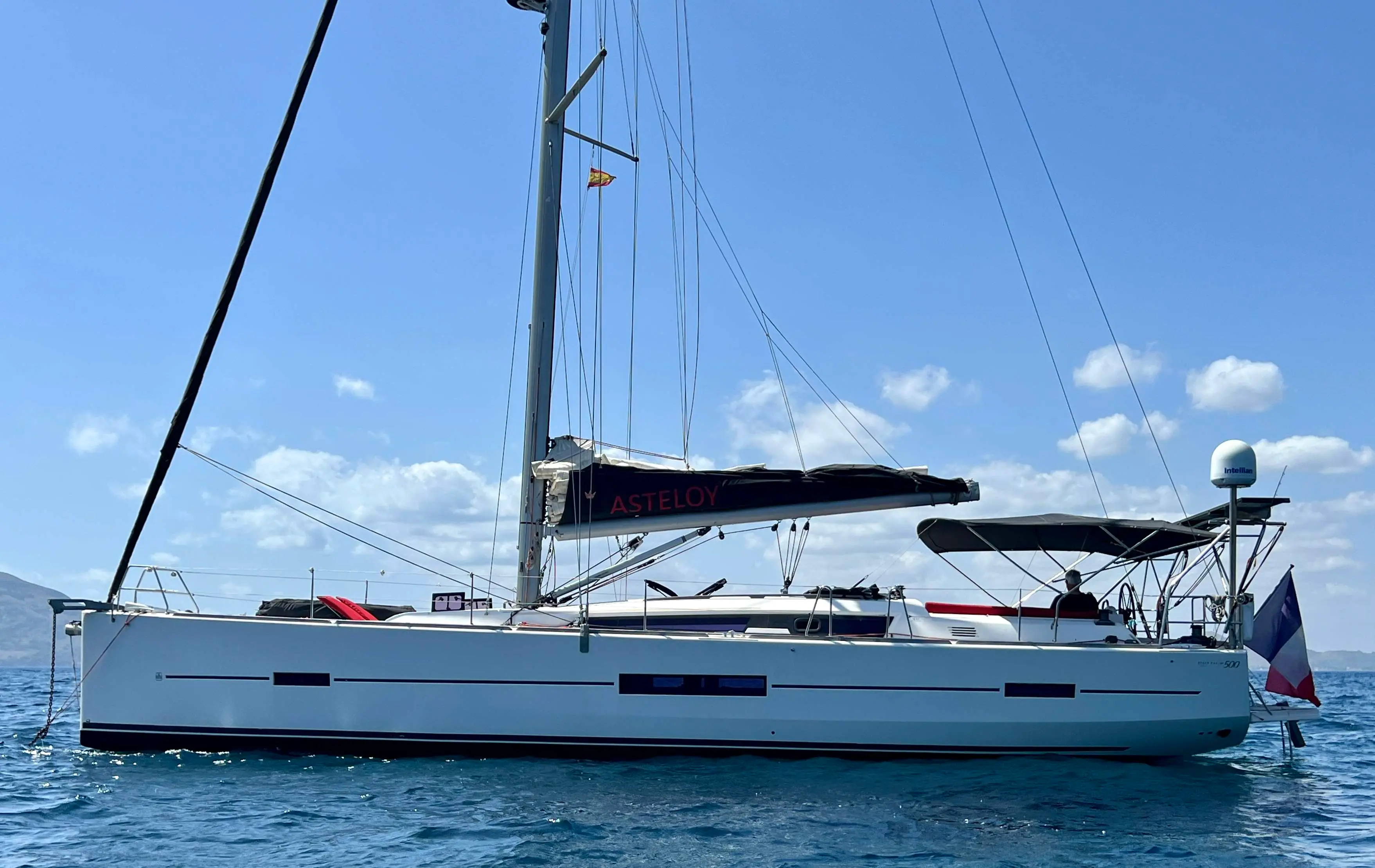 Dufour 500 Grand Large — Voilier blanc vu de profil sur l’eau, avec mât, bimini et pavillon français.