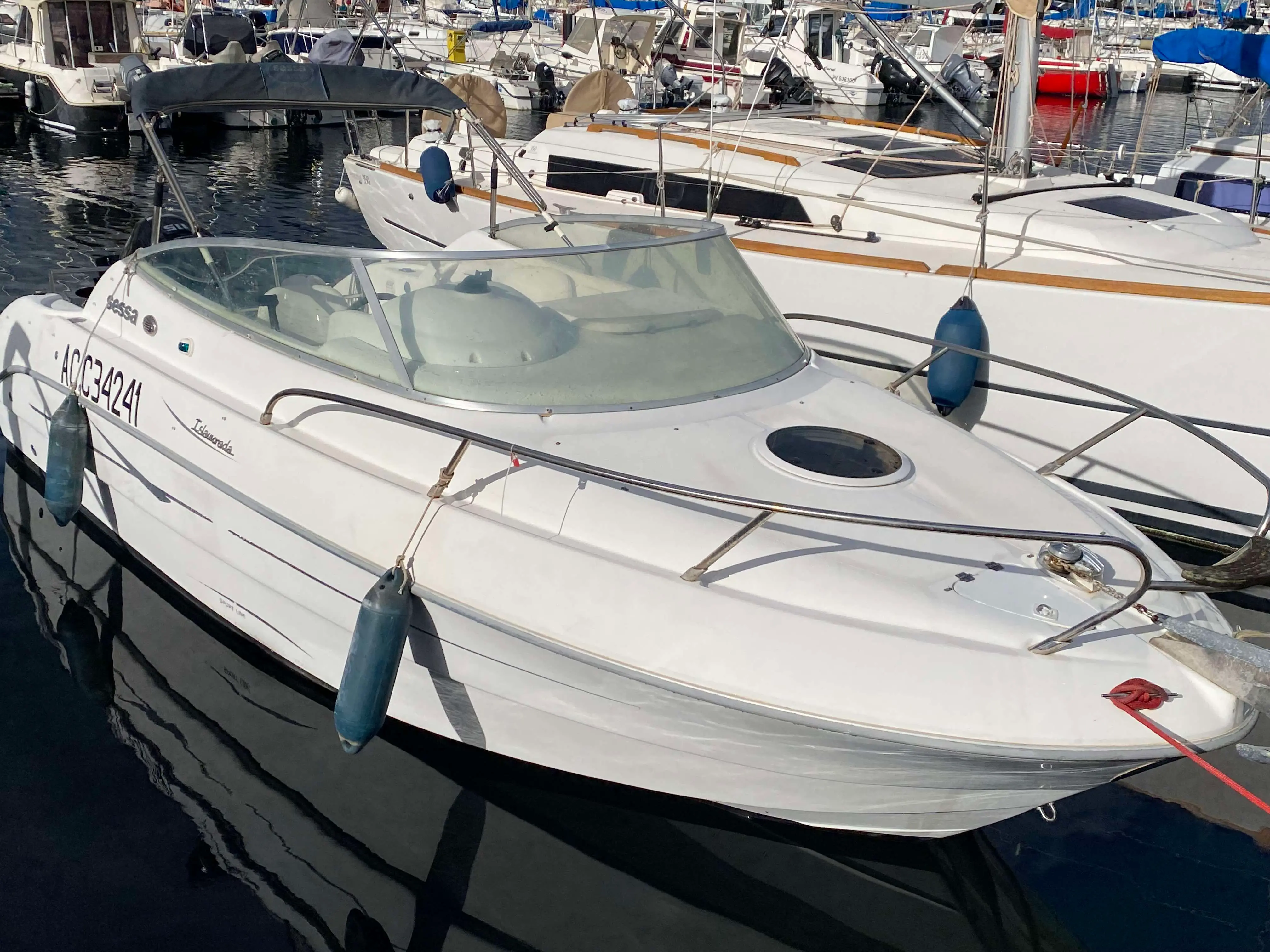 Sessa Marine Islamorada 23 — Bateau à moteur blanc vu de trois quarts avant dans un port, entre d’autres bateaux.