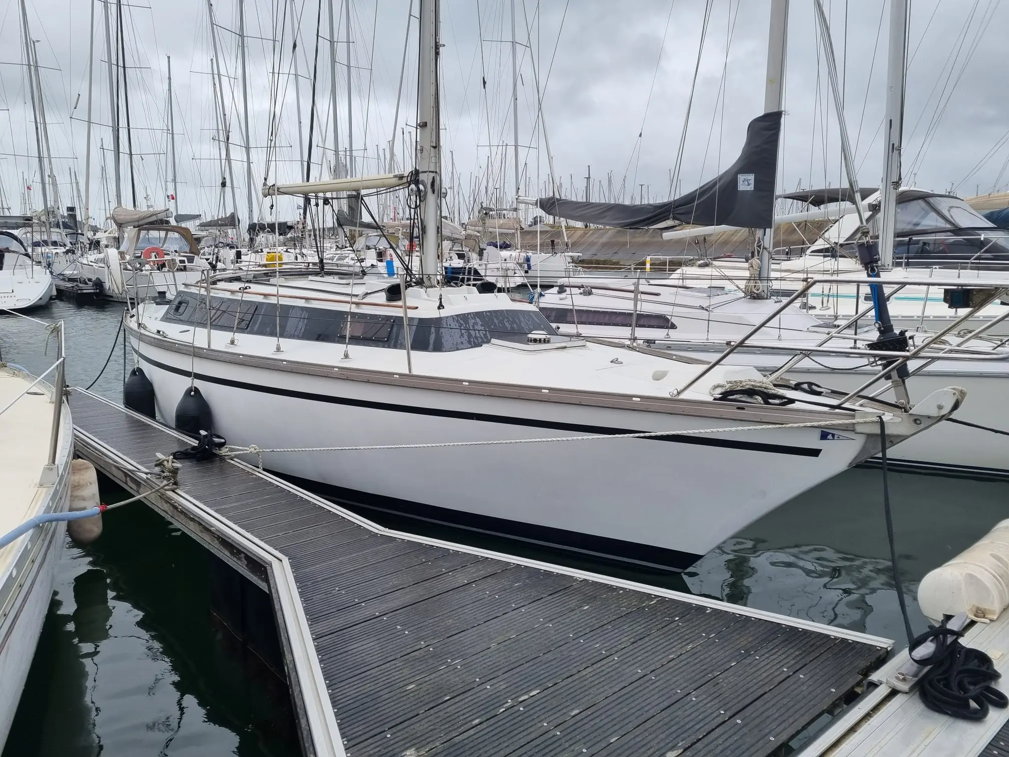 Dufour 31 — Voilier blanc amarré dans une marina, vu de trois quarts.