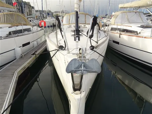 Dufour 335 — Voilier blanc vu de l’avant, amarré entre deux bateaux dans une marina.