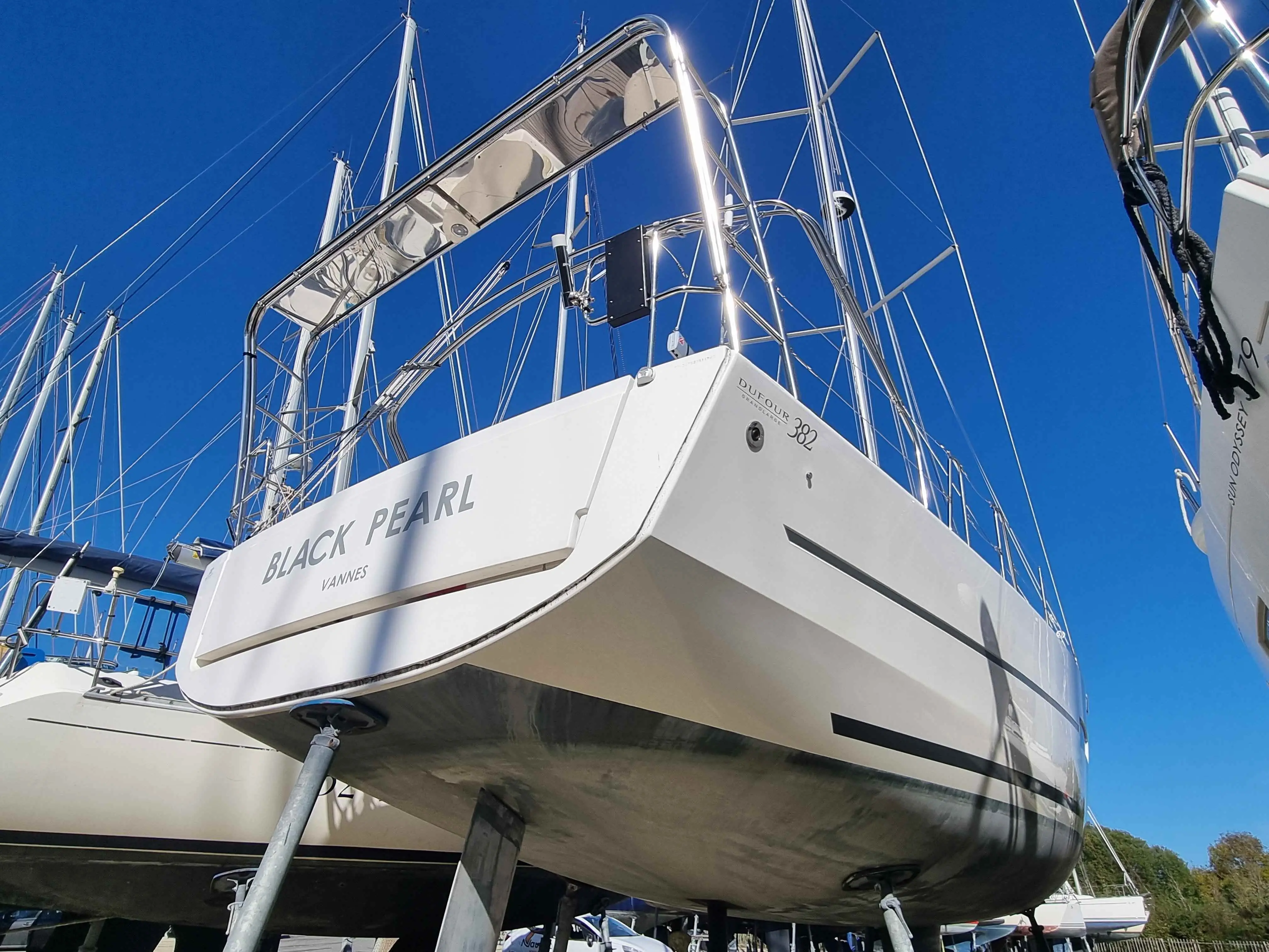 Dufour 382 Grand Large — Voilier blanc vu de l’arrière, sur bers à terre dans un port.